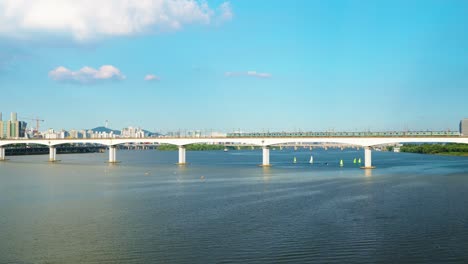 two subway trains traveling in opposite directions meet in the middle of the dangsan railway bridge over the hangang river, with the iconic namsan tower and seoul skyline in background