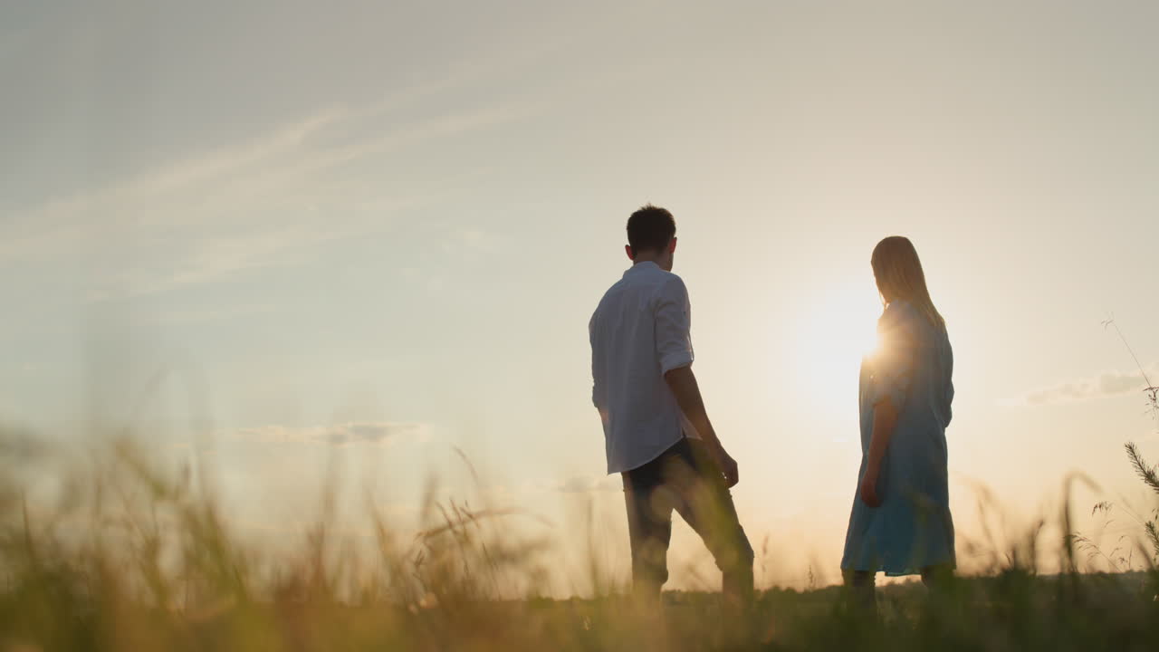 결혼 한 부부는 해가 지는 곳에 서서 앞을 바라보고 있습니다. 관계와 가족 개념.