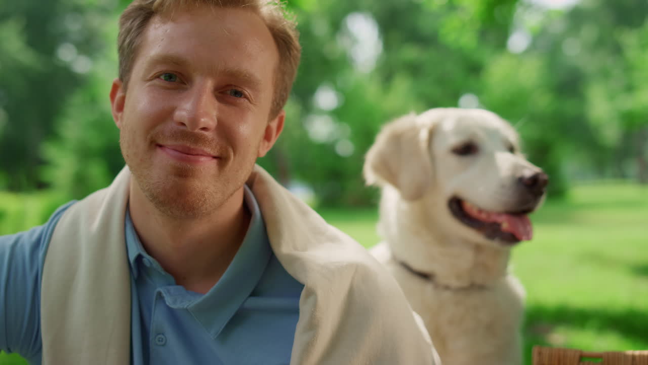 공원에서 아름다운 래브라도와 함께 카메라를 바라보는 웃는 남자의 초상화.