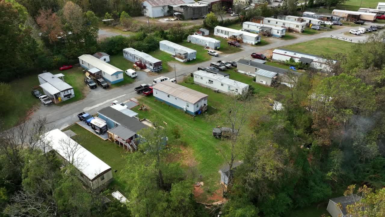 Aerial flyover mobile trailer homes neighborhood in America during sunny day. Low class suburb residential area in autumn season