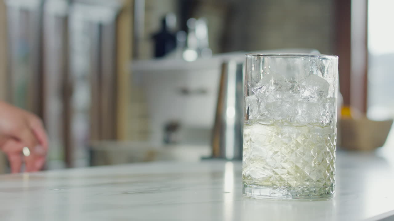Close-up of a bartender placing a glass on the bar, ready to pour a drink