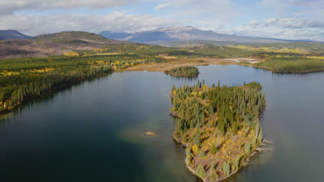 picturesque view of tranquil lake and islet with autumnal forest in british colombia, canada