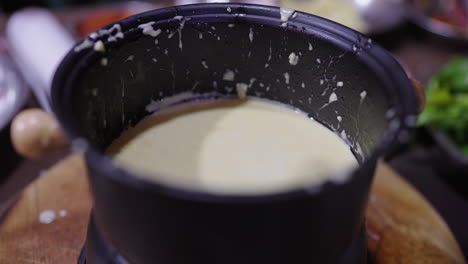 creamy garlic anchovy dip in pot, close-up of rustic bagna cauda preparation