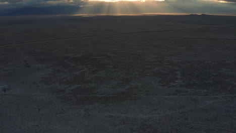 panorámica aérea a través del paisaje desértico hasta los rayos de dios del amanecer a través de las nubes