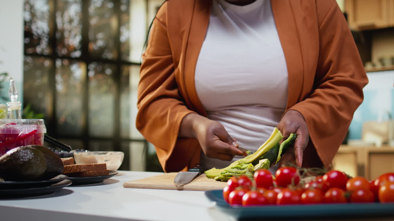 Tagliare l'avocado per il toast, primo piano, video di cucina, donna al bancone.