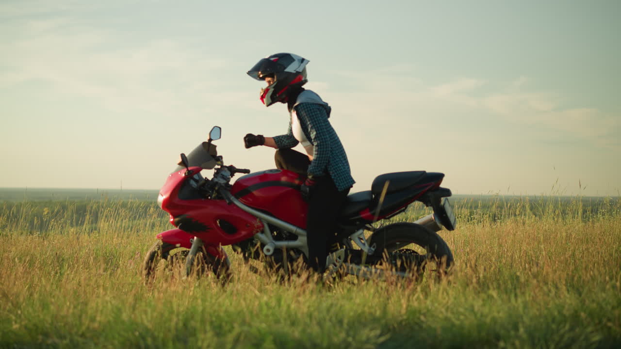 한 젊은 여성이 헬을 착용한 은 잔디에 은 파워 자전거를 타고 누워있는 동안, 그녀는 오토바이에 균형을 잡기 위해 왼손을 사용하여 천천히 자신을 일으킨다.