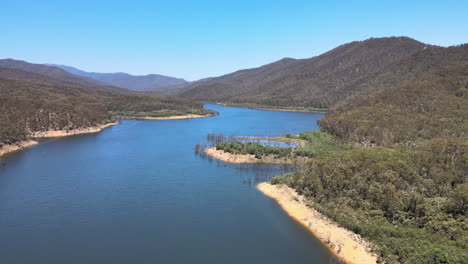 slow moving drone shot of bluewater, green bushland, and mountains near lake eildon, victoria australia