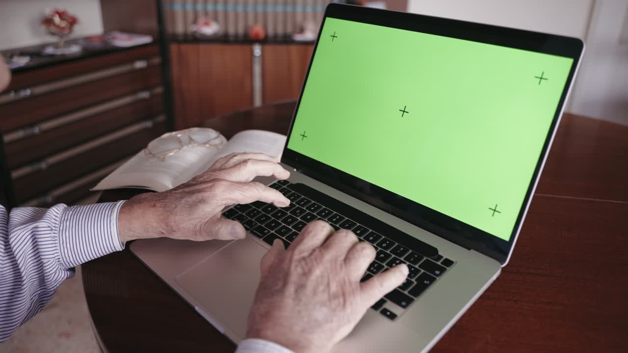 viejo escritor italiano en la jubilación escribiendo en el teclado de la computadora con pantalla verde maqueta de tecla de croma, autor sénior haciendo su historia de vida para la edición del libro. anciano con manos arrugadas escribiendo en el teclato