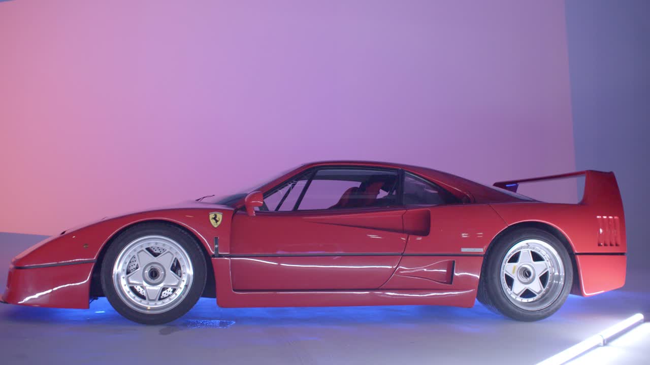 A retro classic red Ferrari F40 the iconic sportscar stands in a studio brightly and well lit. Camera has an handheld movement slowly walking in.