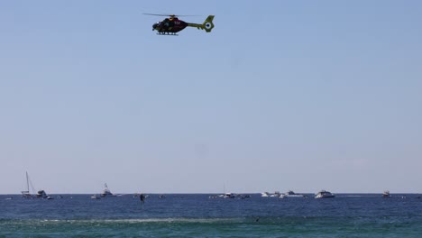 a helicopter flies over the ocean, observing boats