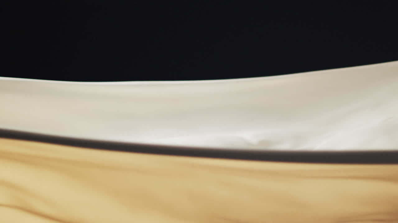 Animation of cream fabric blowing with copy space over black background