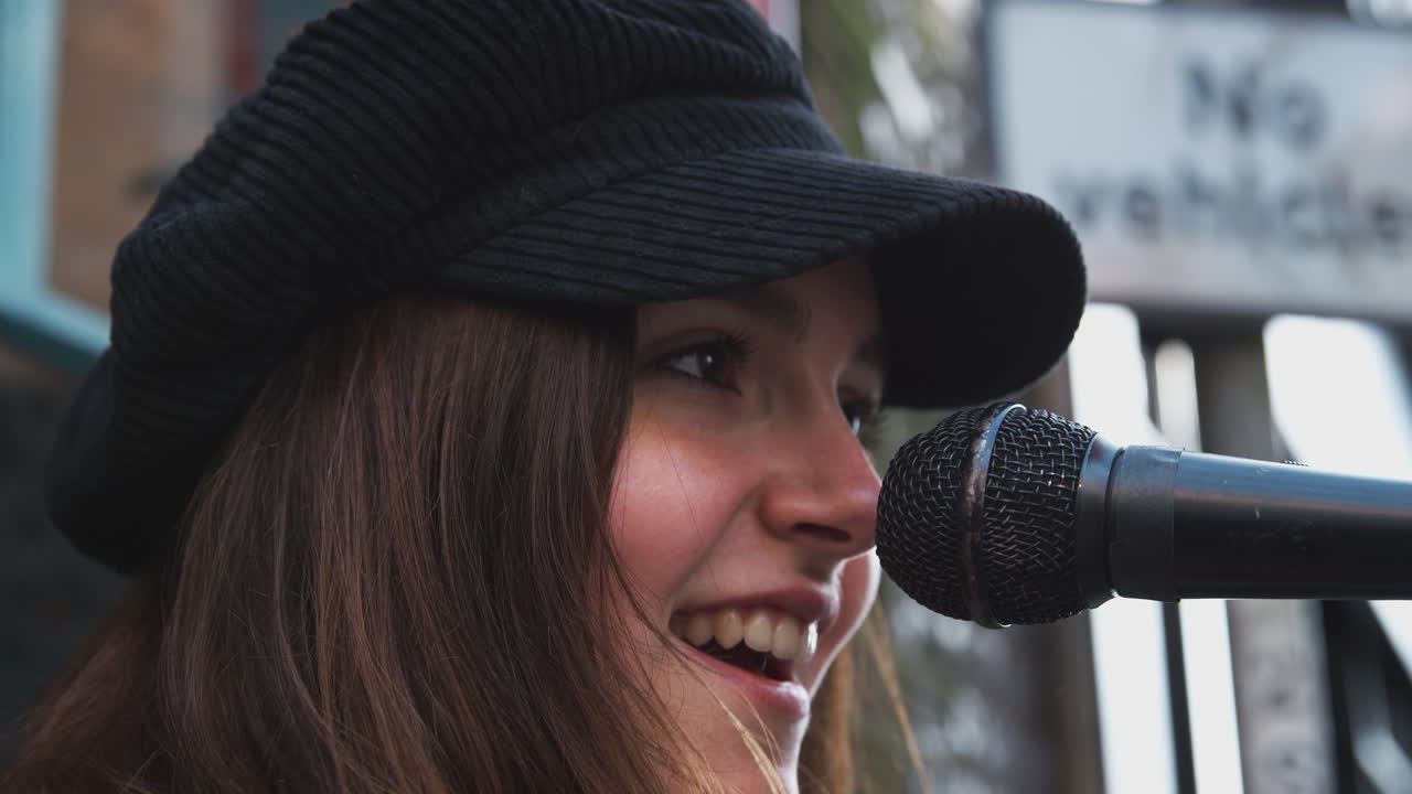 여자 뮤지션 은 거리 에서 야외 에서 어쿠스틱 기타 를 연주 하고 노래 를 부르고 있다