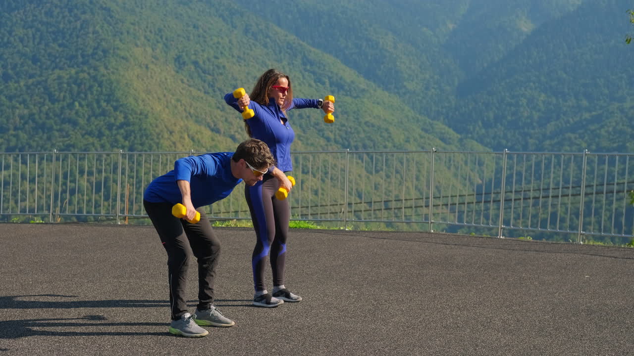 커플 이 야외 에서 덤벨 을 사용 하여 운동 하고 있다