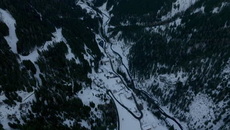 vuelo de aviones no tripulados de carreteras sinuosas de stelvio pasan a lo largo del río entre el denso bosque de coníferas