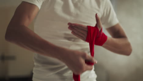 boxer covers hand with wrap for boxing in gym closeup. young athlete applies protective bandage for palms in combat club slow motion. active hobby