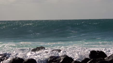 blue waves roll into the coast of hawaii and break on the shore