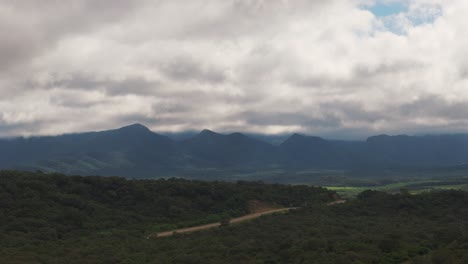 Drone-view-over-green-forest,-along-the-route-close-to-reaching-the-capital-of-Salta,-Argentina