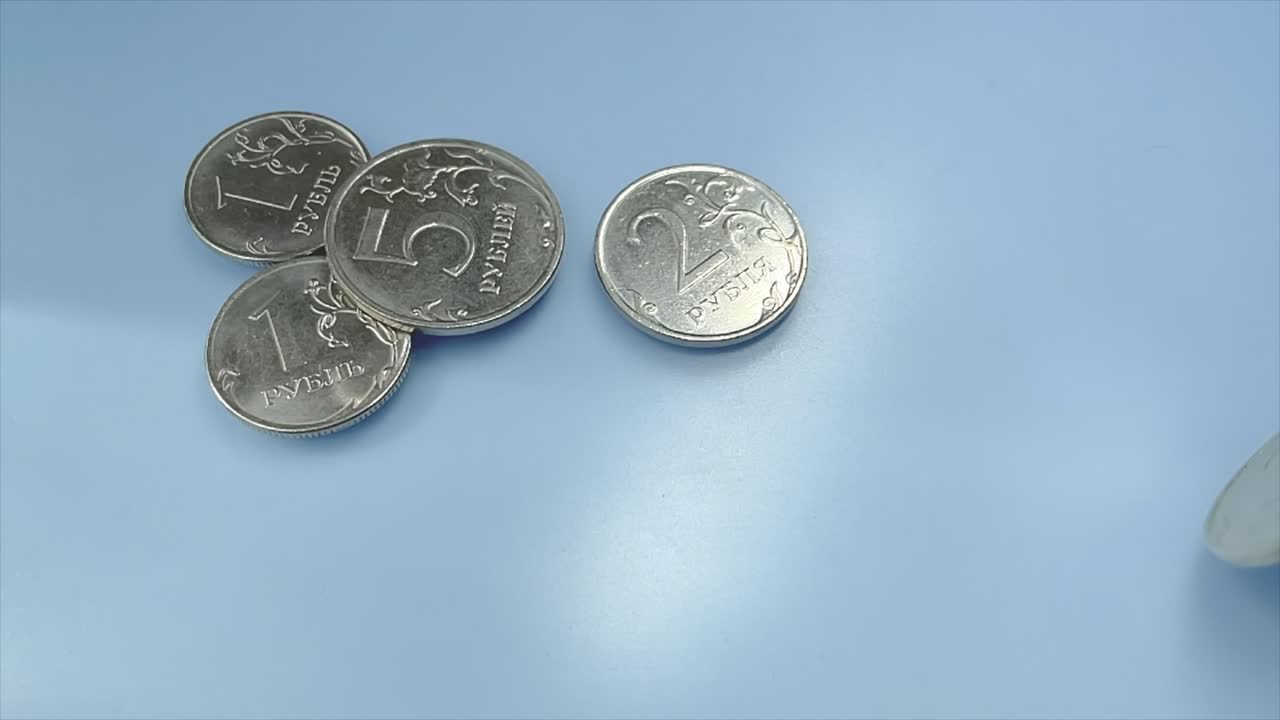 moneda de rublo ruso de metal girando sobre un fondo azul en cámara lenta.