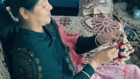 Woman-siting-on-a-bed-and-knitting-with-red-and-black-wool