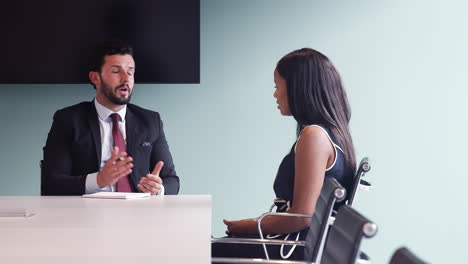 businessman interviewing female candidate at graduate recruitment assessment day in office