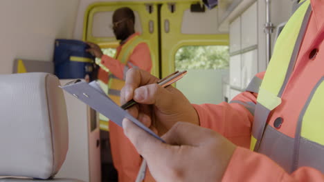 close up of man's hands writing something on a clipboard