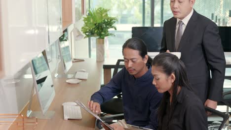 three business people having meeting together with boss discussing the charts and graphs showing the results