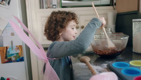 niño feliz horneando en la cocina mezclando ingredientes para cupcakes de chocolate caseros divirtiéndose preparando deliciosas golosinas usando traje de alas de mariposa