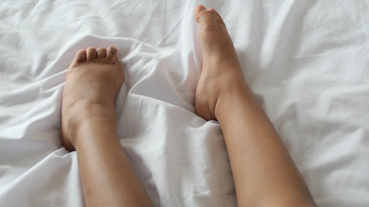 los pies del niño en una cama blanca