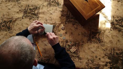 coin evaluator. the collector of coins. the man considers ancient coins.