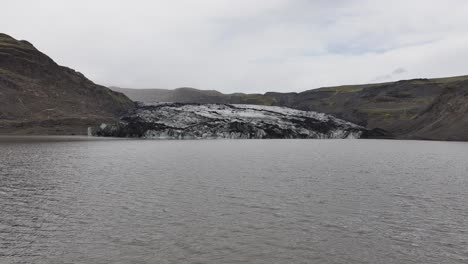 Volando-Sobre-Un-Lago-Glacial-Bajo-Un-Glaciar-En-Las-Tierras-Altas-De-Islandia,-Un-Dron-Disparó-A-60-Fps