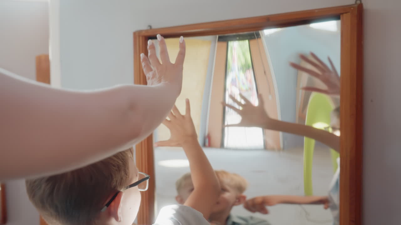 I bambini esplorano i riflessi del vetro curvo. Genitori e figli si divertono insieme con le illusioni degli specchi deformati. I membri della famiglia sperimentano in gruppo varie immagini speculari alterate e distorte.