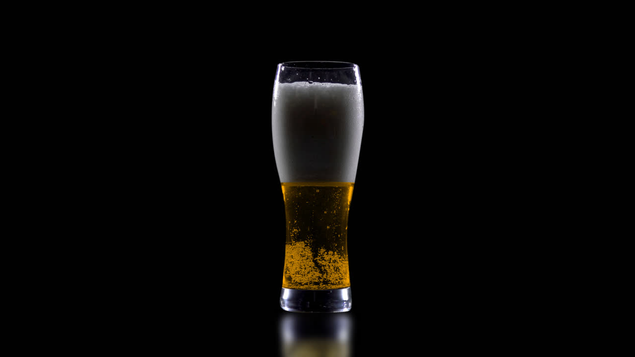 un vaso de cerveza sobre un fondo negro