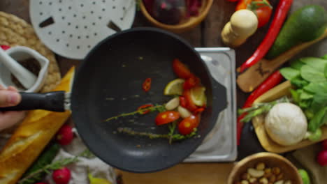 draufsicht auf eine bratpfanne mit gemüse, die ein koch bewegt