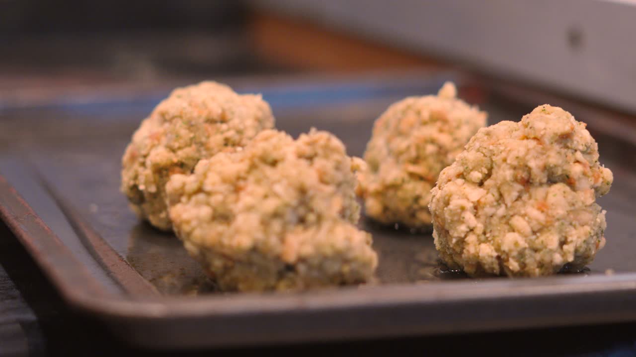 Female Hand Placing Down Sage and Onion Stuffing Balls on Baking Tray Ready to Cook. Breadcrumbs and Seasoning Mixed with Oil, Butter, Water to Accompany Roast Dinners. Home cooking