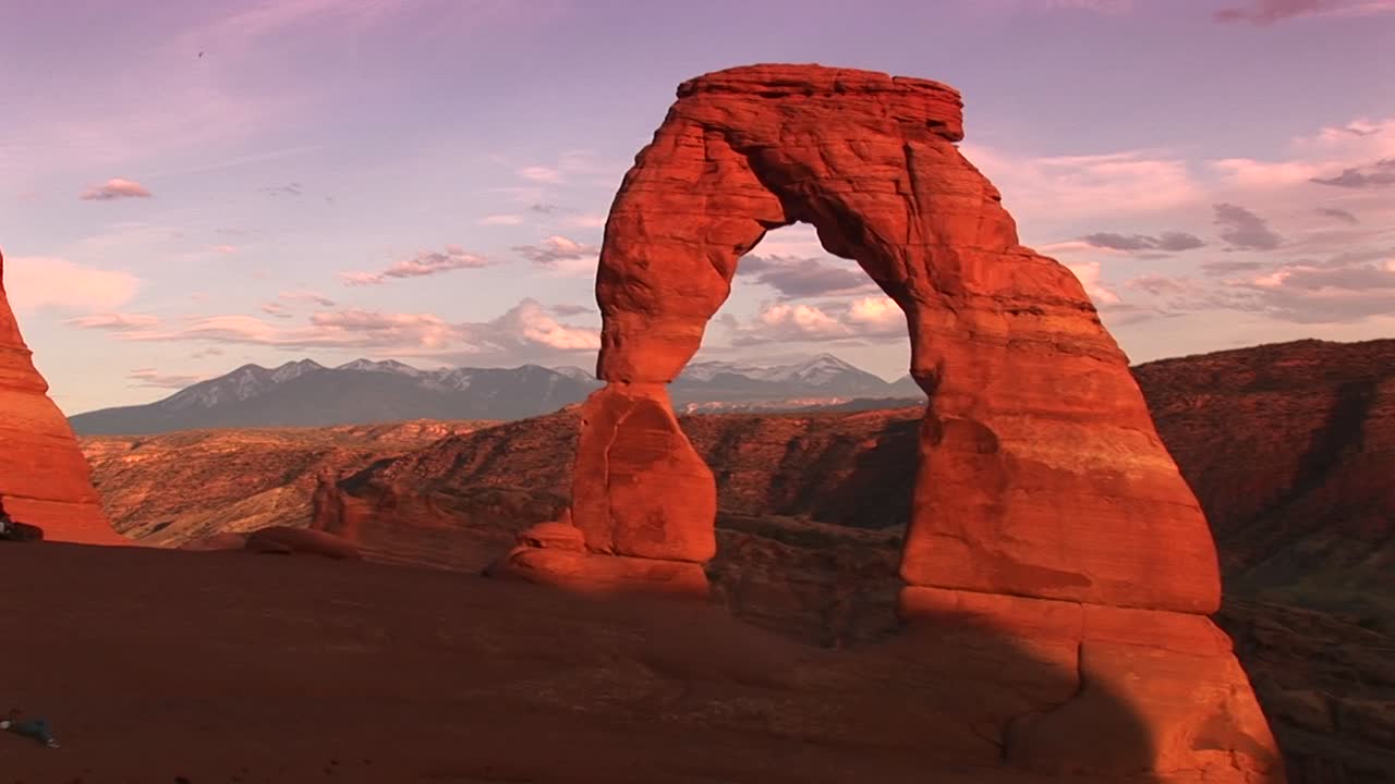 Pemandangan Luas Delicate Arch di Taman Nasional Arches, Utah, dengan Pegunungan di Latar Belakang