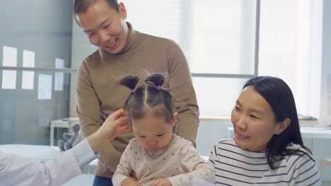 asian pediatrician talking with parents of toddler girl