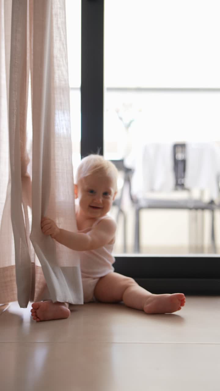 bebé escondiéndose detrás de la cortina con el perro