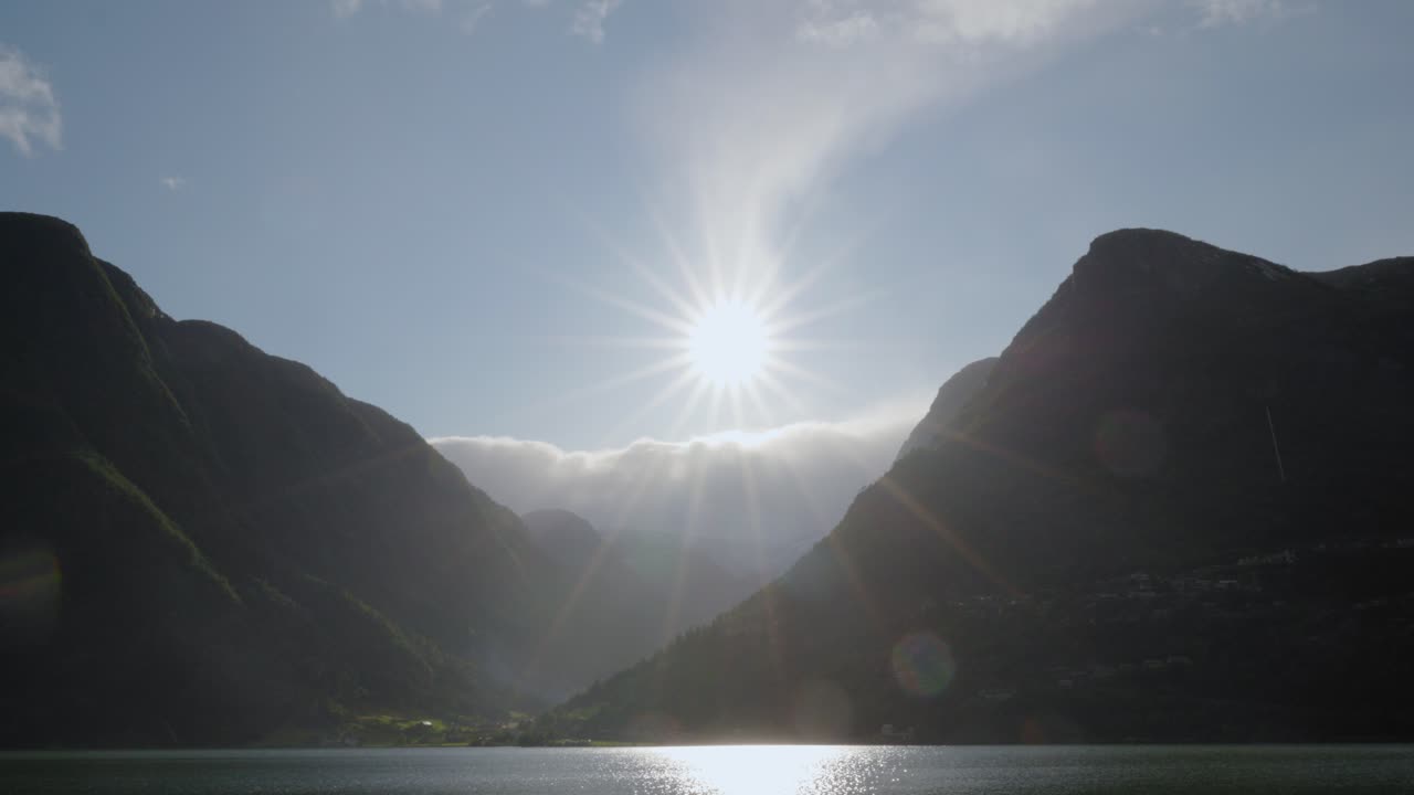 Pan over mountains at Sandvevatnet, blue skay and rain, sun flares
