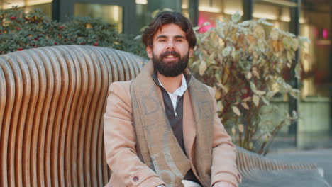 indian man freelancer sitting on city street closes laptop finishing working online distant job