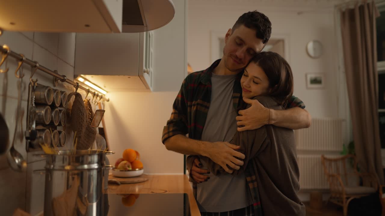 um casal a abraçar-se na cozinha.