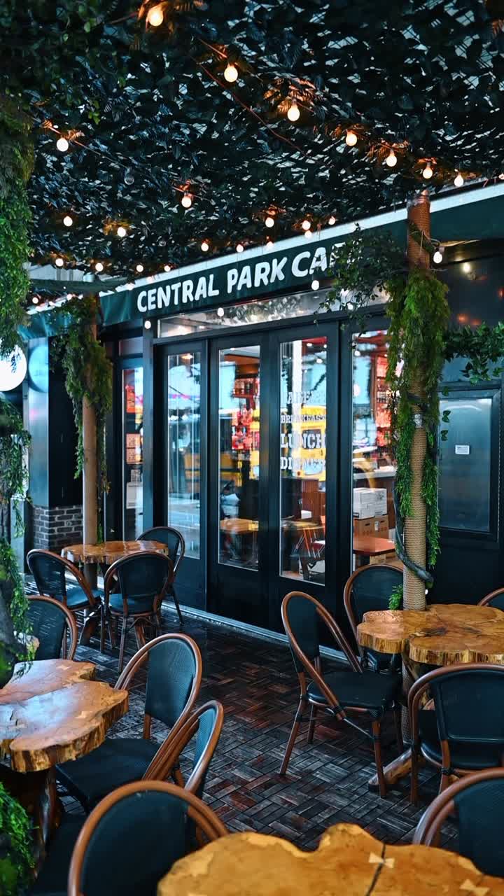 New York, USA, 5 agosto 2025: Ingresso al Central Park Cafe con patio e vegetazione. Vista di una terrazza di ristorante con mobili in legno, luci a catena e piante rampicanti decorative a New York.