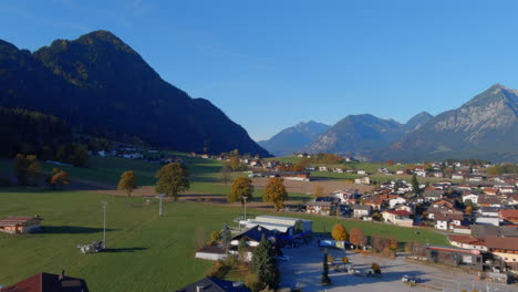 breathtaking calm flight towards mountains above town in austria, drone push in
