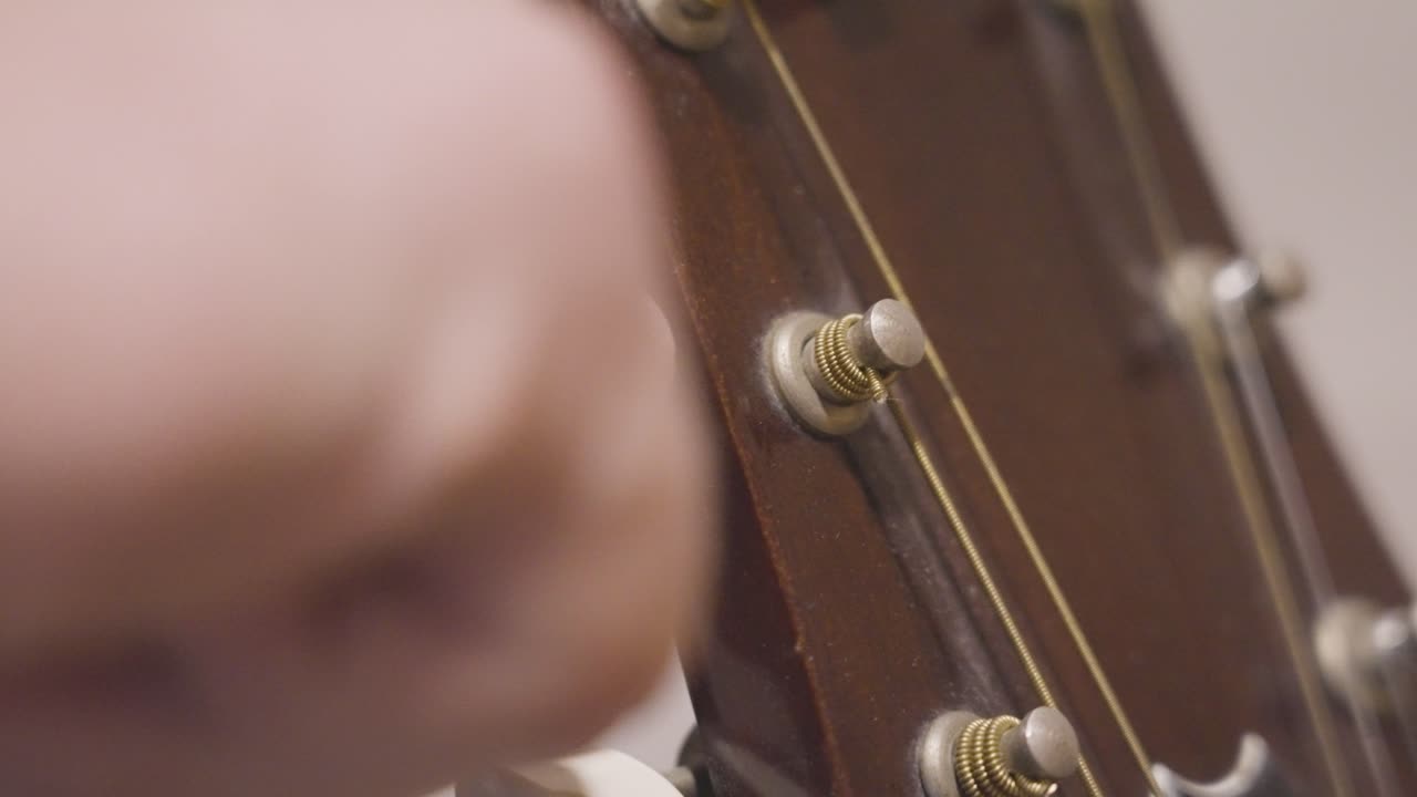 Turning the tuning peg of an old acoustic guitar