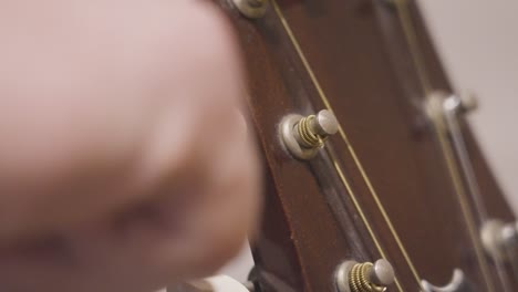 turning the tuning peg of an old acoustic guitar