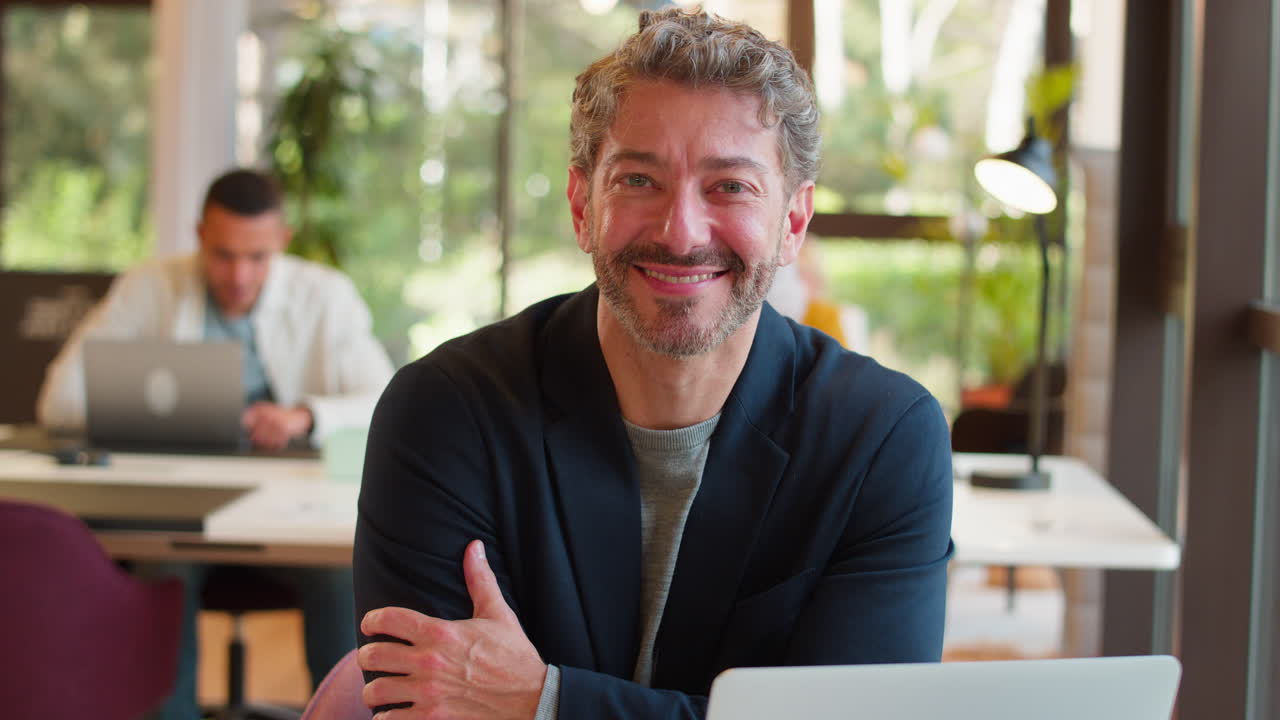 Ritratto di uomo d'affari maturo sorridente che lavora al laptop alla scrivania in ufficio.
