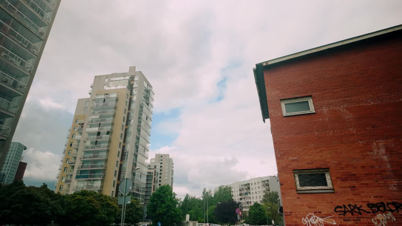 View of modern skyscrapers juxtaposed with old Soviet-era brick buildings adorned with graffiti in Imanta district of Riga. Contrast between new and old architecture. Location: Imanta, Riga, Latvia