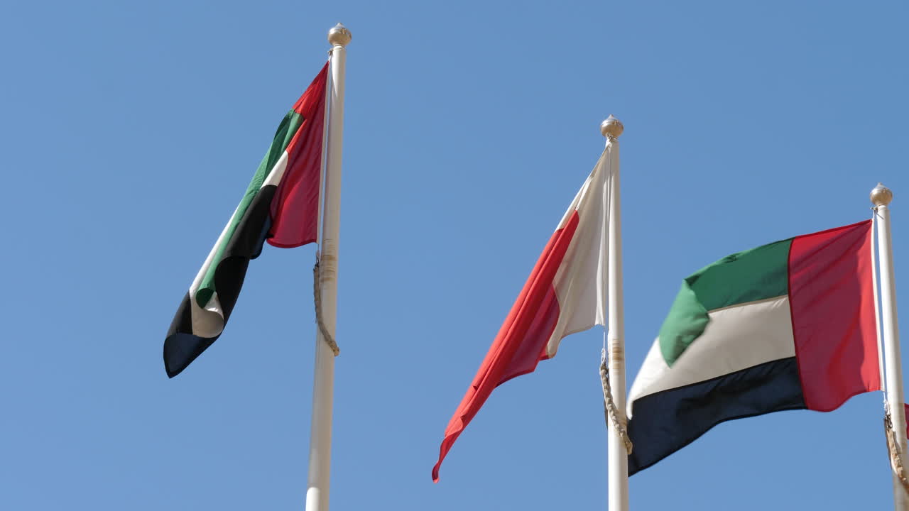 banderas de dubai y emiratos árabes unidos ondeando en el viento contra el cielo azul