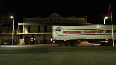 trucks and cars pass by an old, illuminated building at night