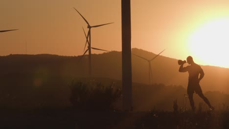 atleta al atardecer trenes con un kettlebell. tiro de silueta. el concepto de energía respetuosa con el medio ambiente