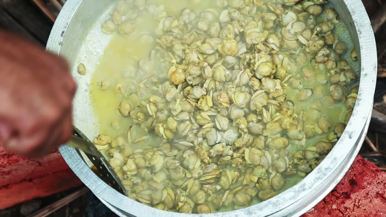 black clam meat, Turmeric powder is added and the meat cooked in water is stirred with a small spoon ,traditional outdoor cooking